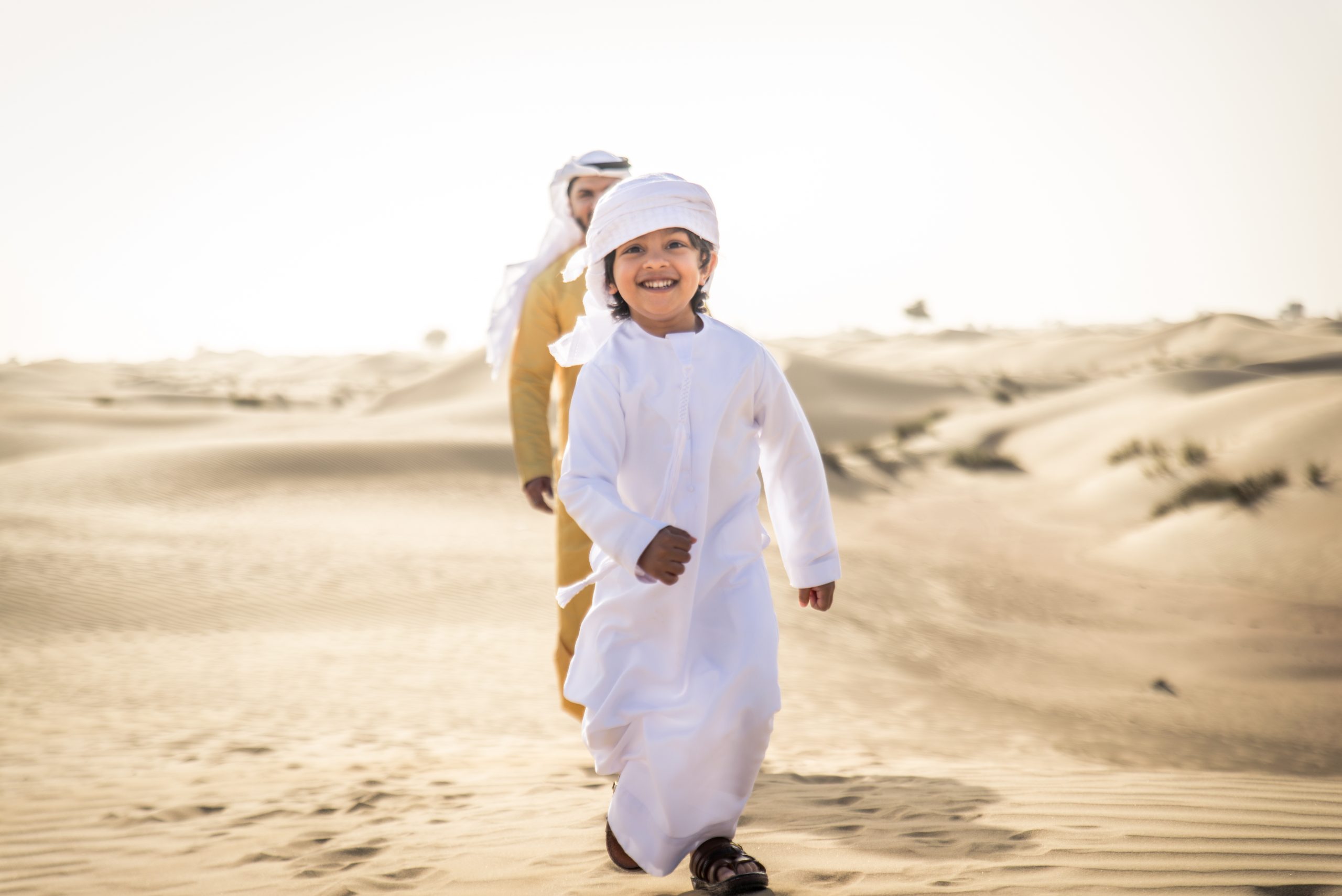 Happy family playing in the desert of Dubai -  Playful father and his son having fun outdoors
