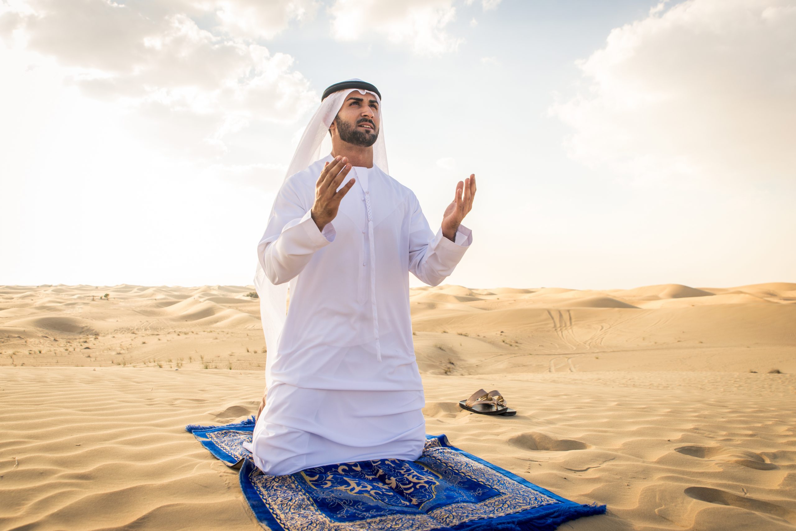 Arabian men witk kandora walking in the desert - Portrait of two middle eastern adults with traditional arabic dress